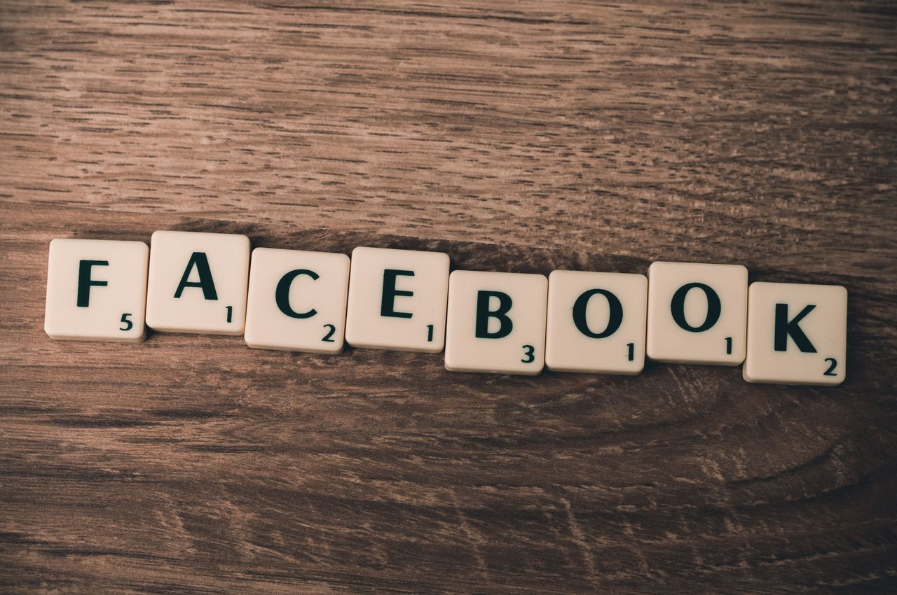 about-01 Scrabble tiles spelling Facebook on a wood background, symbolizing social media.